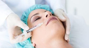 Portrait of beautiful young woman getting botox cosmetic injection in her face.