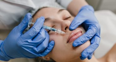 Closeup portrait young woman doing botox procedures by professional. Injection, making lips, modern devices, technology, medicine, cosmetology therapy
