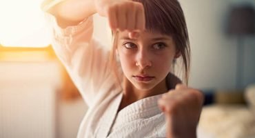 Closeup portrait of little girl aged 10 practicing karate in her room. The girl is lit by sunlight from the window.